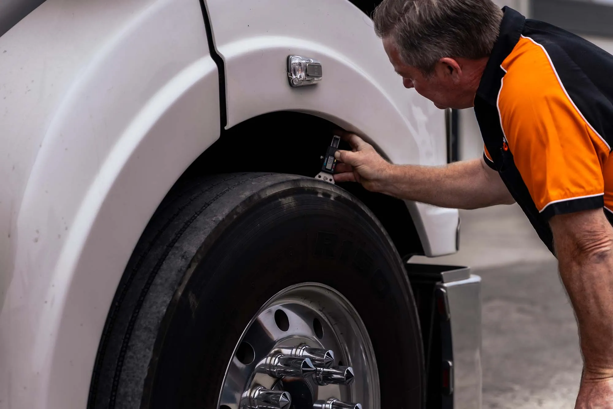 A Williamson Tyreco technician measuring a heavy truck's tyre tread depth